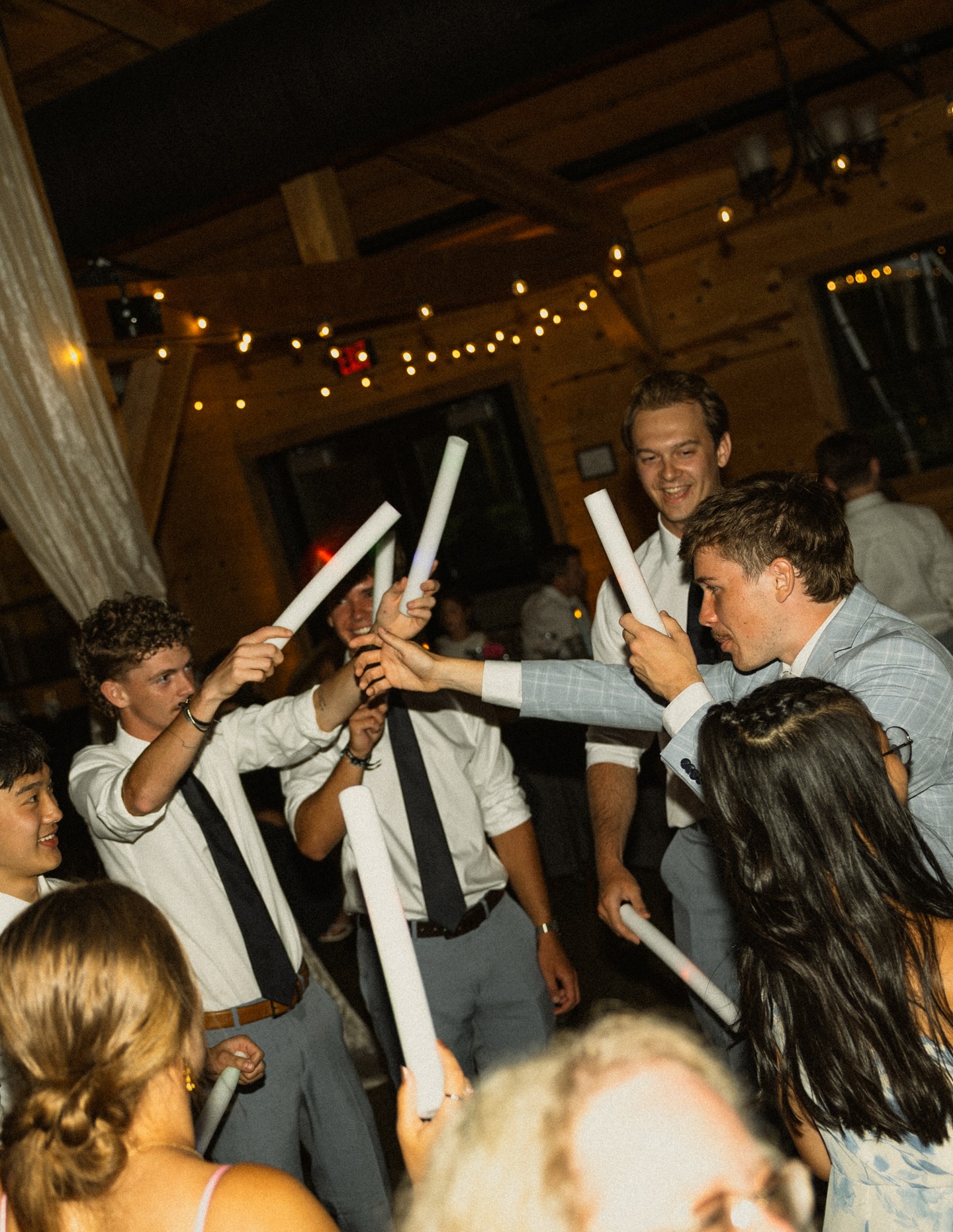 Wedding guests forming a dance circle with foam sticks at The Barn at Bull Meadow